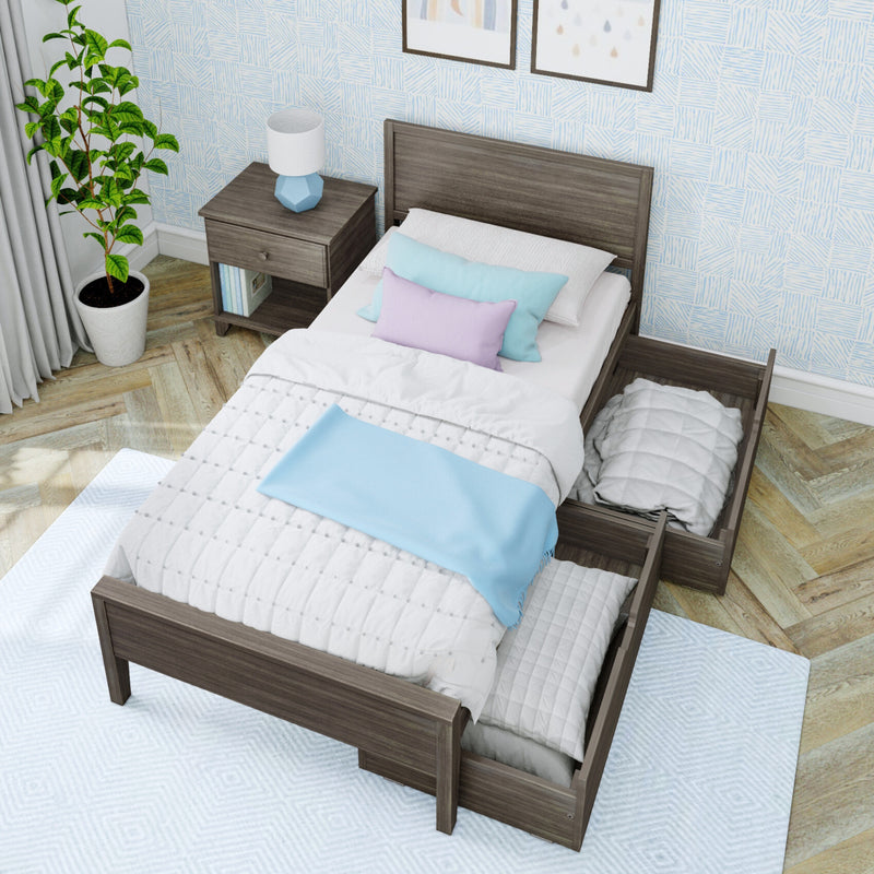 Modern small bedroom interior featuring a single wooden storage bed with open under-bed drawers, pastel blue and lavender bedding, a wooden nightstand with blue lamp, potted plant, light blue patterned wallpaper, and herringbone hardwood floor