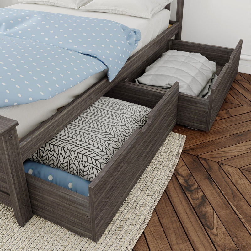 Gray wooden twin bed with pull-out under-bed storage drawers, patterned pillows and blue polka-dot duvet on hardwood floor with woven rug