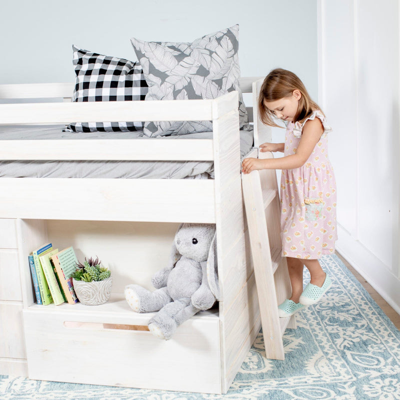 White wooden loft bed with ladder in bright kids' bedroom, little girl climbing, gray checkered and leaf-print pillows, stuffed bunny, bookshelf and blue patterned rug