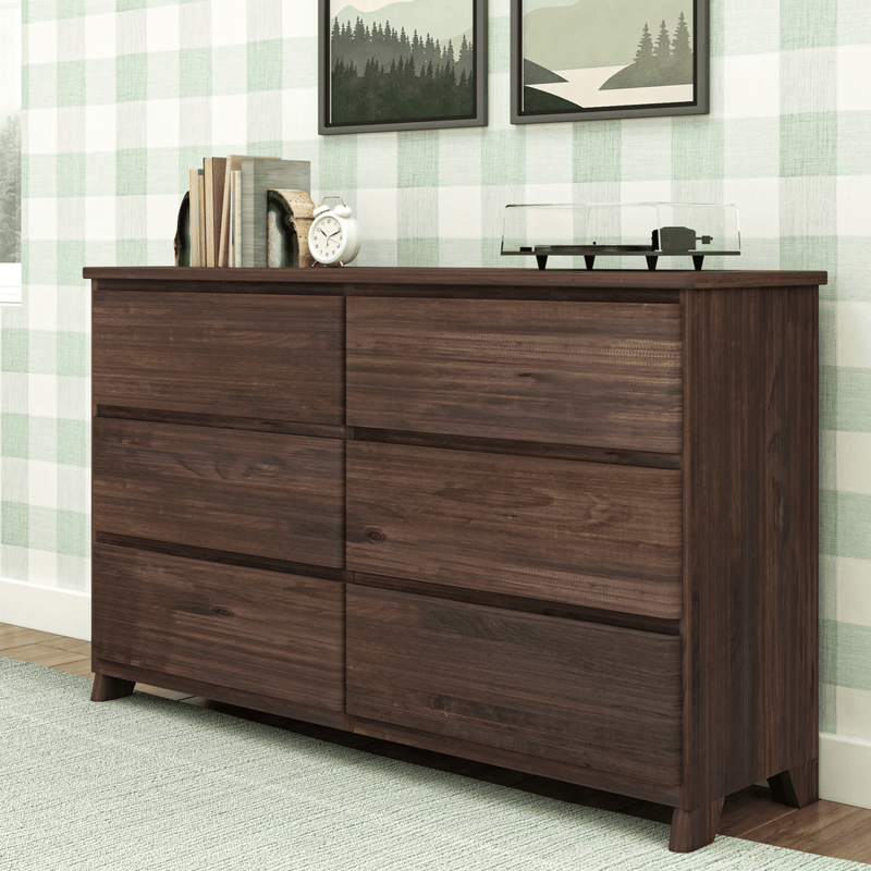 Dark walnut mid-century modern dresser topped with stacked books, a white alarm clock and a turntable, styled against mint green buffalo plaid wallpaper with framed forest prints and a light green textured rug.