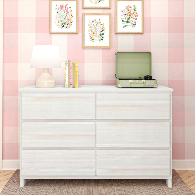 Nursery with pink gingham wallpaper, white wooden dresser, table lamp, stacked books, floral framed prints and a mint green record player — pastel girls room decor