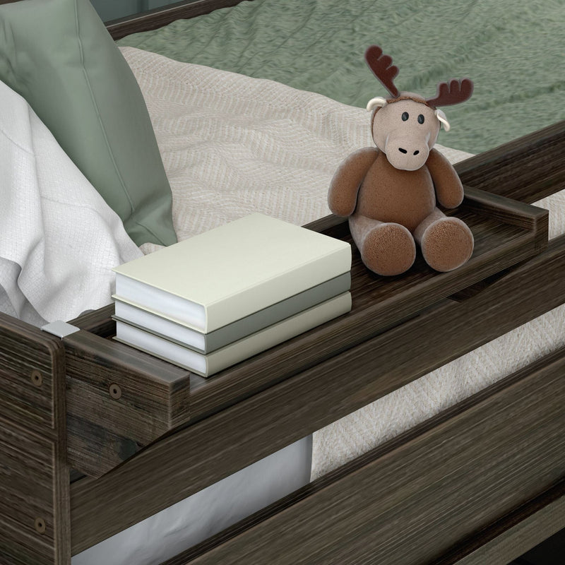 Plush moose stuffed animal sitting on a wooden bed tray beside stacked books and sage green bedding, cozy nursery/bedroom decor