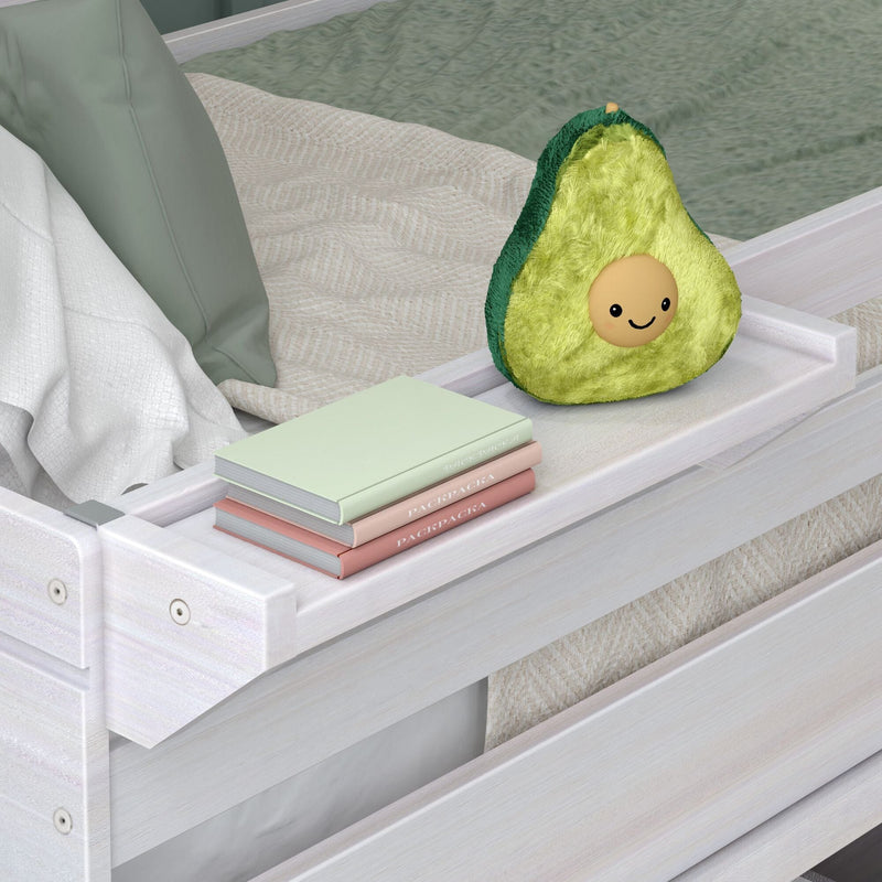Cute avocado plush on white wooden bed tray with pastel books and cozy green bedding, nursery decor
