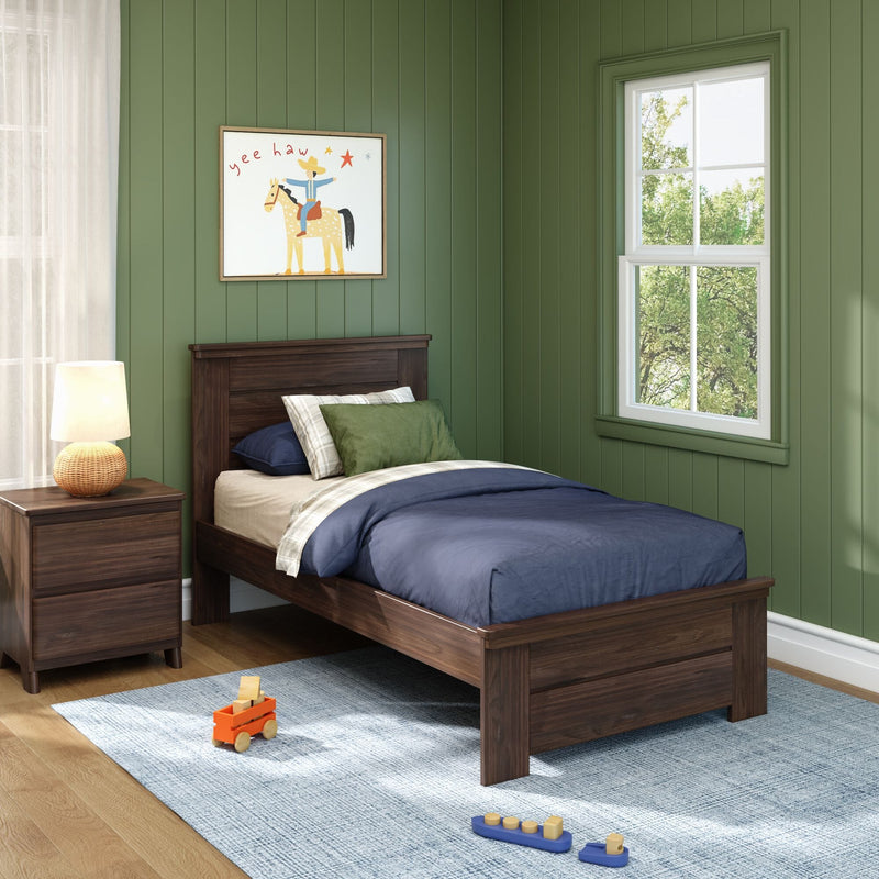 Children's bedroom decor: green vertical paneled walls, dark wood twin bed with green and plaid pillows, framed cowboy wall art, bedside lamp, toy truck and wooden blocks on blue rug by sunlit window