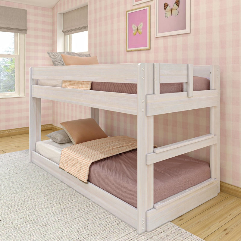 Whitewashed wooden bunk bed in pink gingham kids' bedroom with beige and blush bedding, butterfly wall art and sunlit window