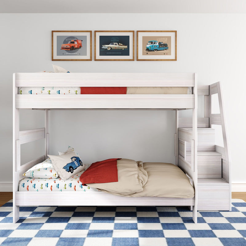 White wooden loft bunk bed with car-themed bedding and pillows, framed vintage car prints, red throw and blue check rug in kids' room