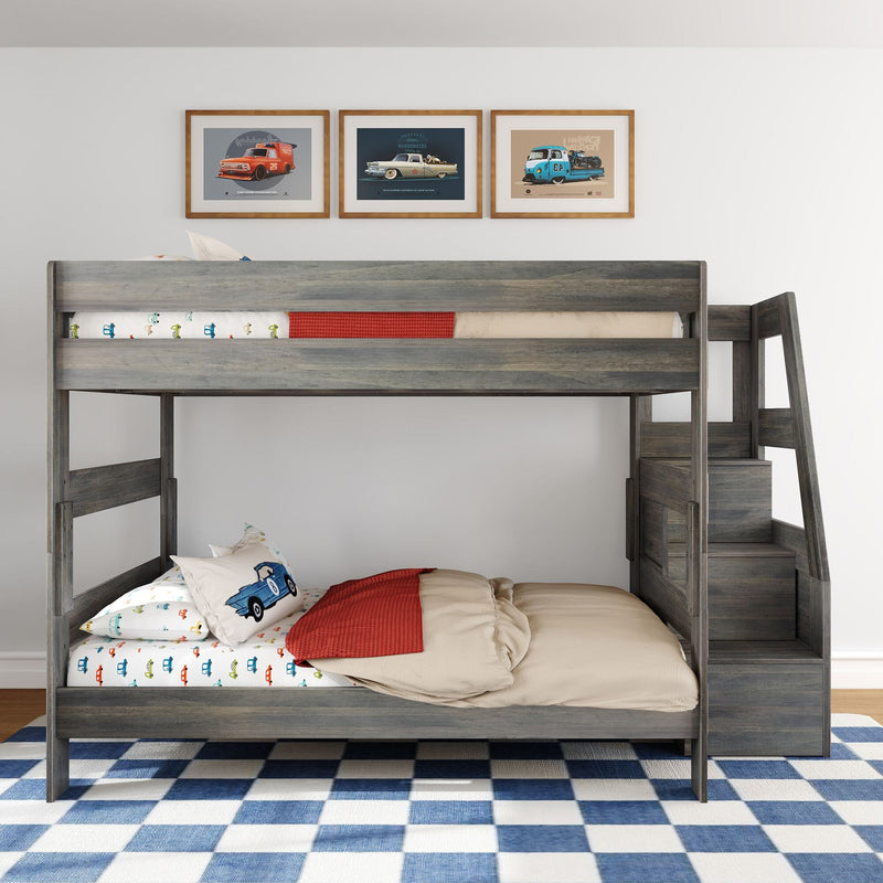 Grey wooden loft bunk bed with car-themed sheets and pillow, red blanket, framed vintage car prints and blue check rug in children's bedroom