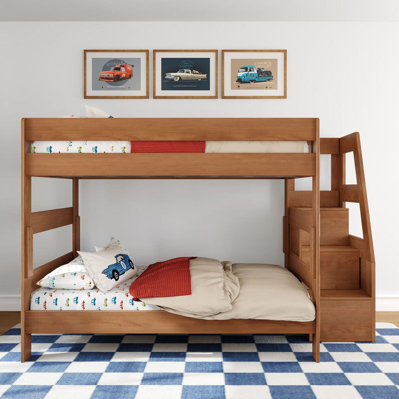 Solid wood bunk bed in children's bedroom with car-themed bedding, framed vintage car prints, storage stairs and blue check rug