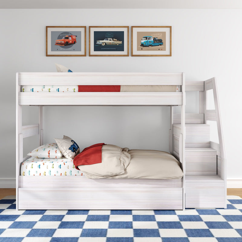 White wooden loft bunk bed with staircase, car-themed sheets and pillows, framed vintage car prints on wall and blue checkered rug in children's bedroom