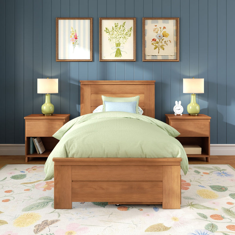 Cozy bedroom interior with wooden bed and green bedding, matching nightstands and lamps, blue paneled wall, framed botanical prints and floral area rug