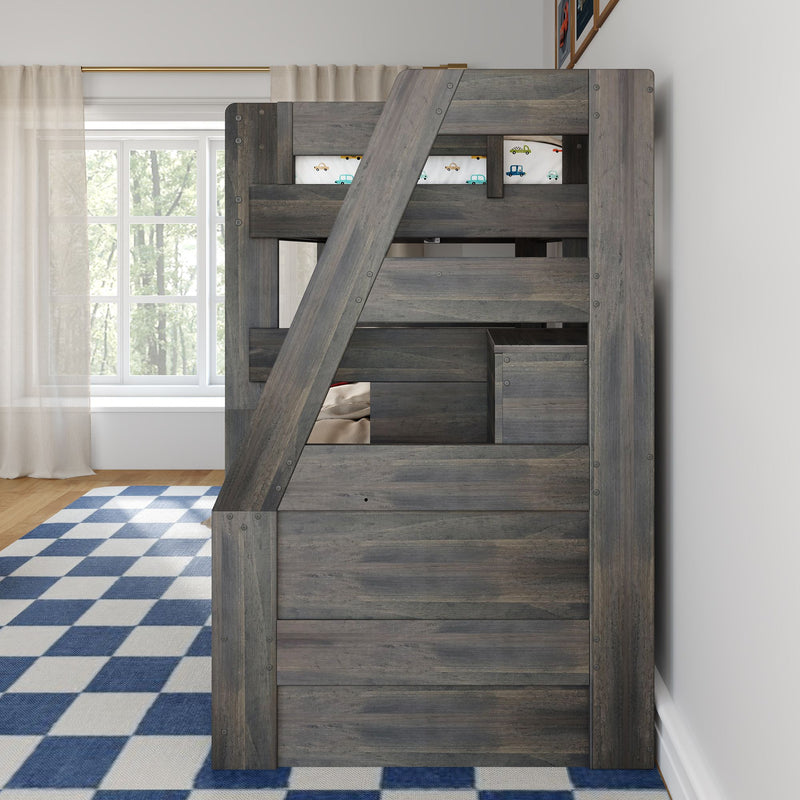 Gray wooden kids' loft bunk bed with angled ladder and built-in storage drawers, car-print bedding, blue checkered rug and sheer curtains in a bright children's bedroom