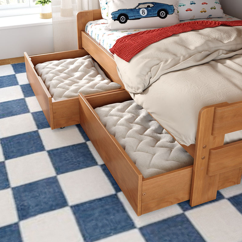 Wooden kids bed with pull-out under-bed storage drawers, car-print bedding, red knit throw and blue checkered rug — toddler bedroom storage solution