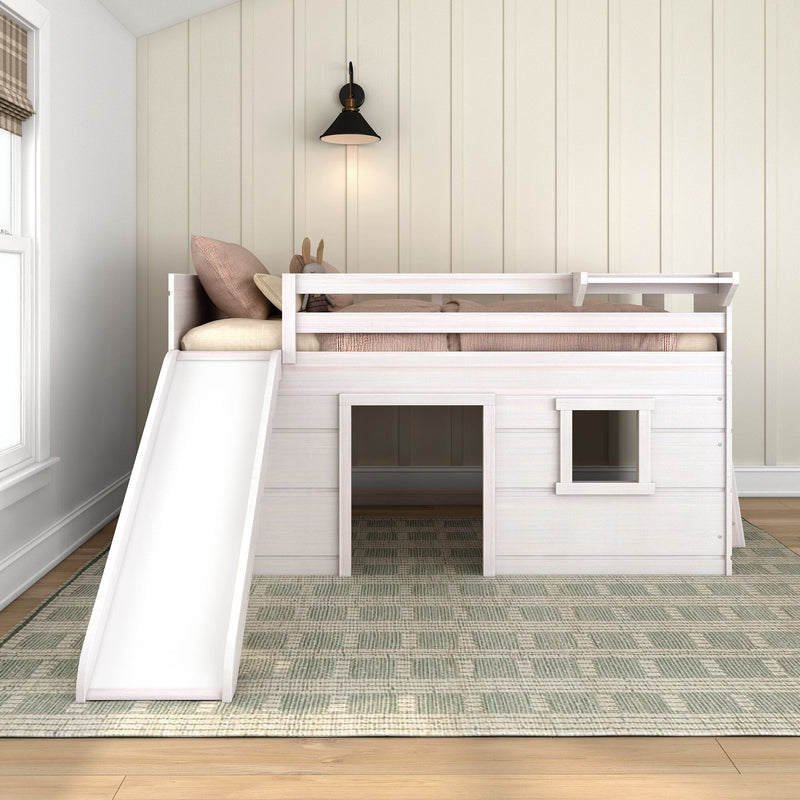 White wooden kids loft bed with slide and playhouse, beige shiplap wall, black wall sconce, blush pillows and stuffed bunny in neutral nursery