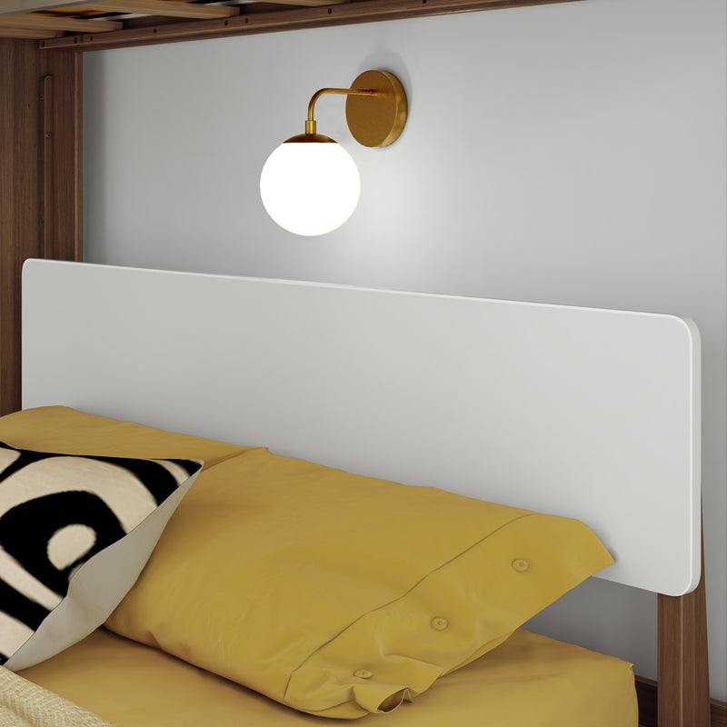 Modern brass wall sconce with white globe over white headboard and mustard-yellow bedding in a minimalist bedroom