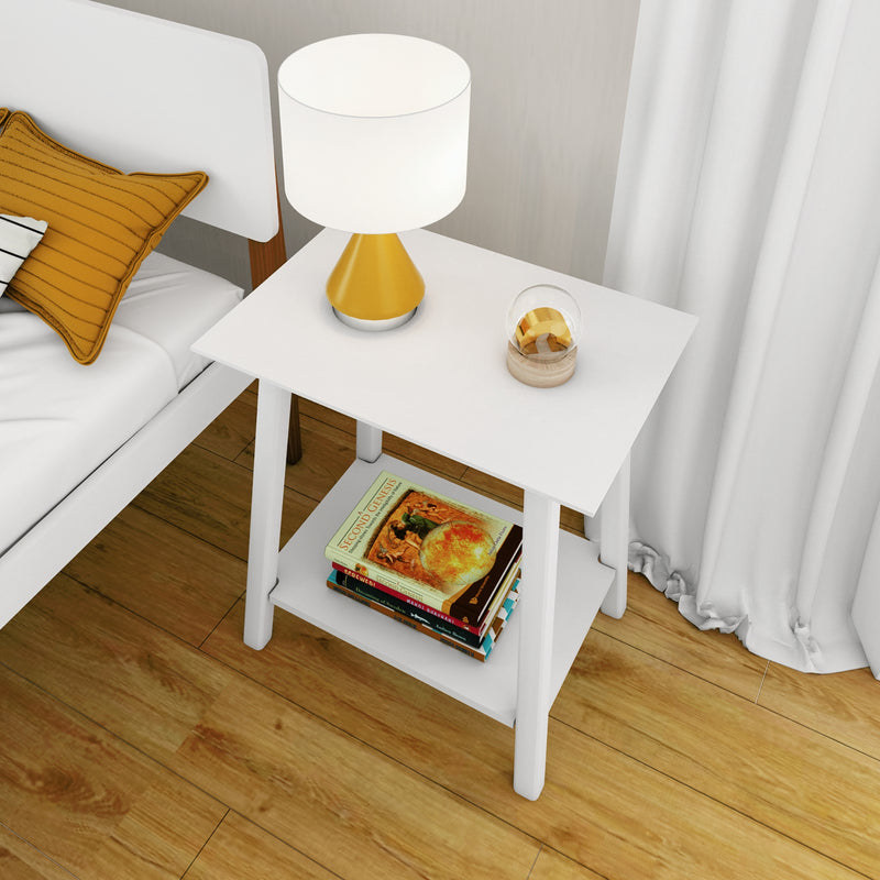Minimalist white nightstand in a modern bedroom with a yellow table lamp and white shade, mustard accent pillow on the bed, stack of books on the lower shelf, wood plank flooring and white curtains