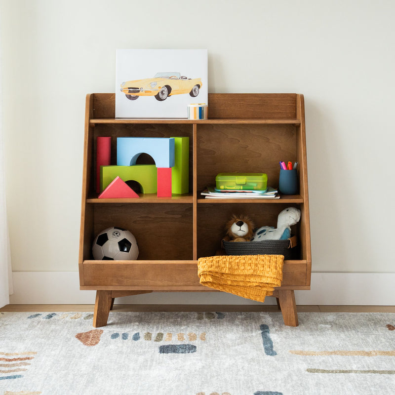 Wooden mid-century toy shelf in children's playroom with colorful foam blocks, stuffed animals, soccer ball and yellow blanket