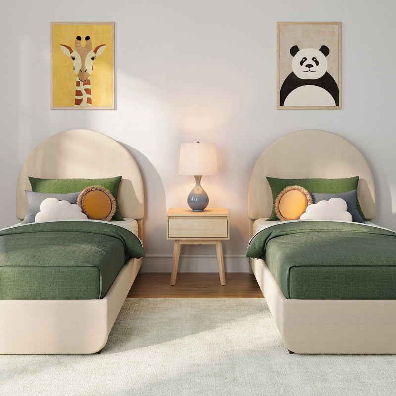 Cozy children's bedroom with twin beige headboards and green bedding, decorative cloud and round pillows, wooden nightstand with lamp, and framed giraffe and panda nursery wall art
