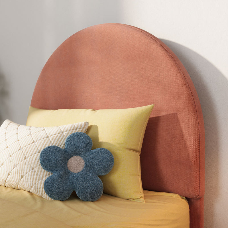 Coral round upholstered headboard with yellow bedding, quilted cream pillow and blue flower-shaped cushion in a modern styled bedroom