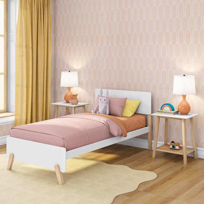 Pastel children's bedroom with pink twin bed, yellow curtains, peach geometric wallpaper, wooden nightstands with orange lamps and plush bunny toy