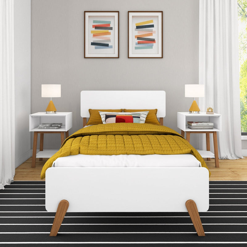 Modern minimalist bedroom interior with white bed frame, mustard quilted duvet and patterned pillow, mid-century bedside tables with yellow lamps, black-and-white striped rug, framed abstract wall art and neutral gray walls illuminated by natural light