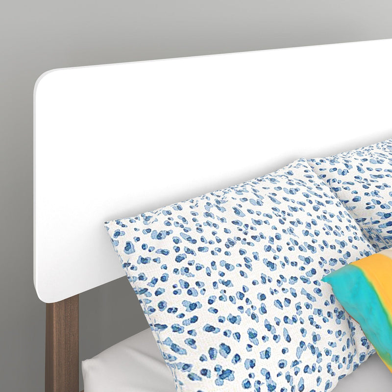 Close-up of modern white rounded headboard with wooden legs and blue spotted leopard-print pillow and bedding