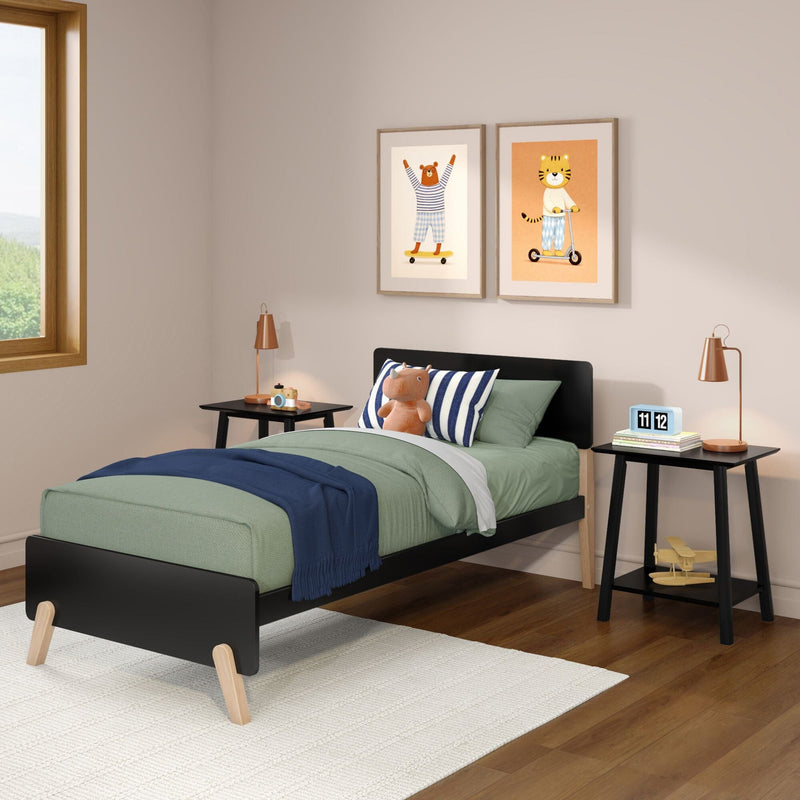 Kids bedroom decor with green twin bed, striped pillows and plush toy, framed animal wall art, black bedside tables with copper lamps, hardwood floor and natural window light