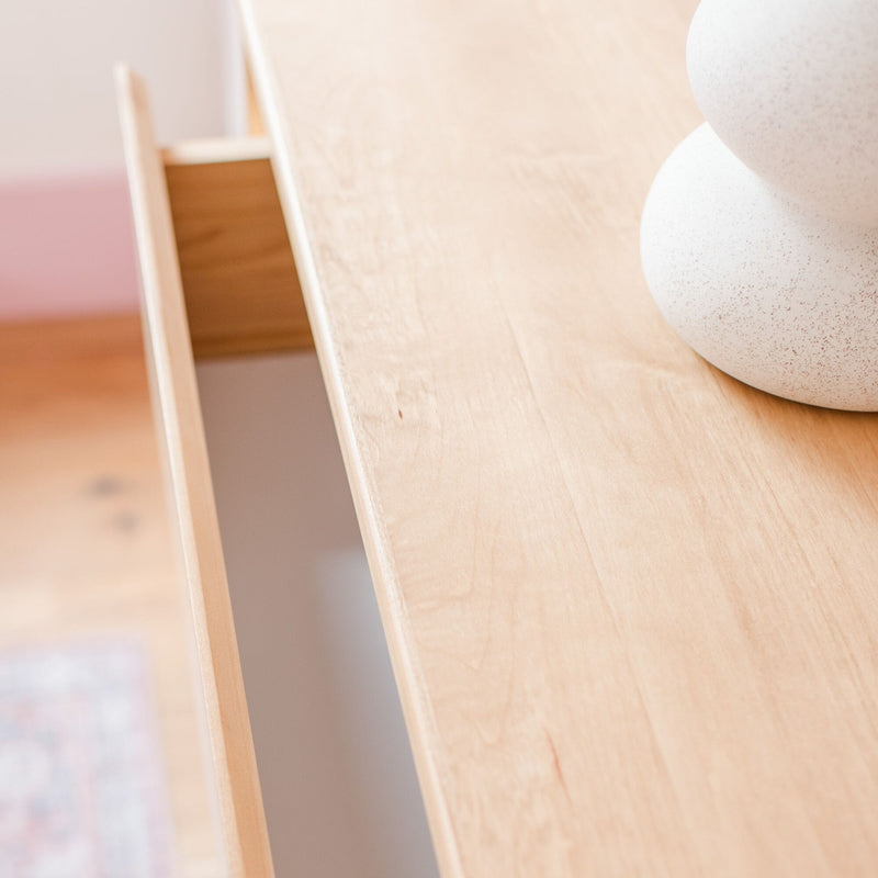 Close-up of a minimalist light oak tabletop with an open drawer and speckled white ceramic vase, Scandinavian home decor