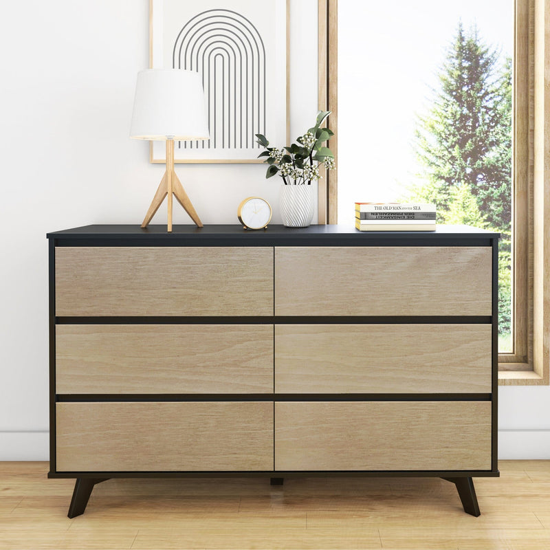 Modern mid-century six-drawer wood dresser with black frame styled with table lamp, clock, potted plant and books by a sunny window