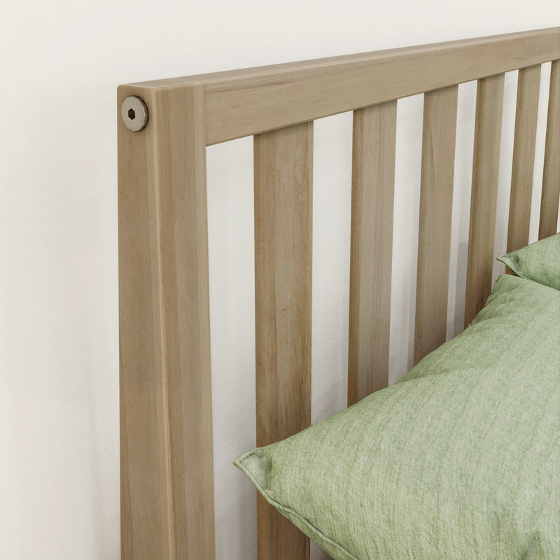 Close-up of a modern light oak slatted wooden headboard with vertical slats and green bedding in a minimalist bedroom