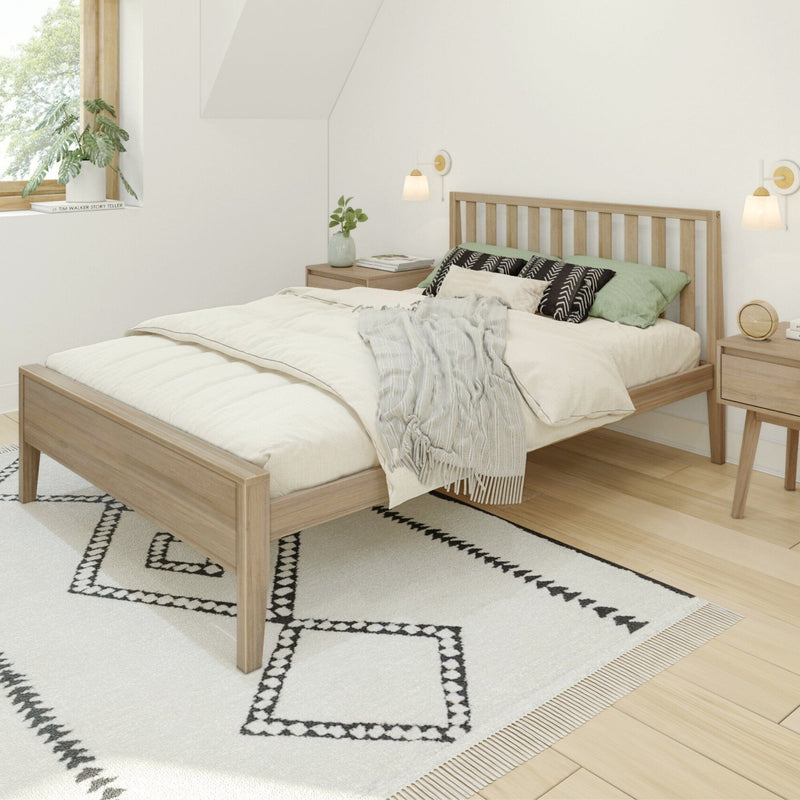 Minimalist Scandinavian bedroom interior with light wood bed frame, neutral bedding and throw, green accent pillows, black-and-white patterned rug, wooden bedside tables, wall sconces and potted plant by a sunlit window