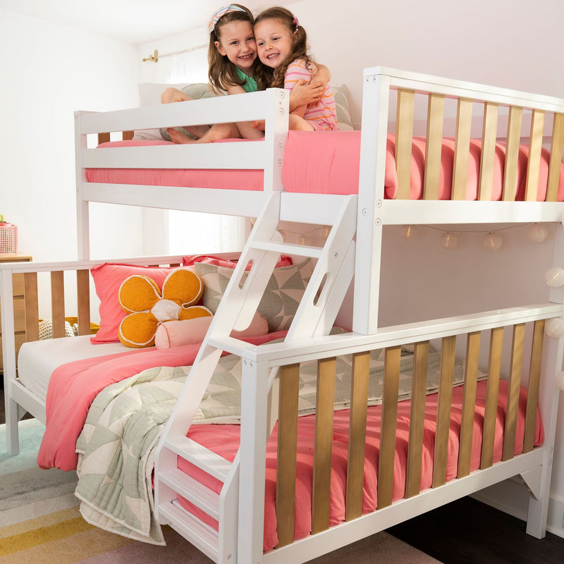 White wooden bunk bed with pink bedding and two smiling girls on the top bunk in a bright modern kids' bedroom