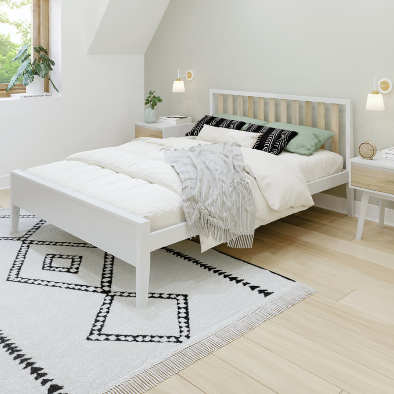 Minimalist Scandinavian bedroom with white wood bed frame, neutral bedding and gray throw, black geometric rug, bedside lamp and potted plant