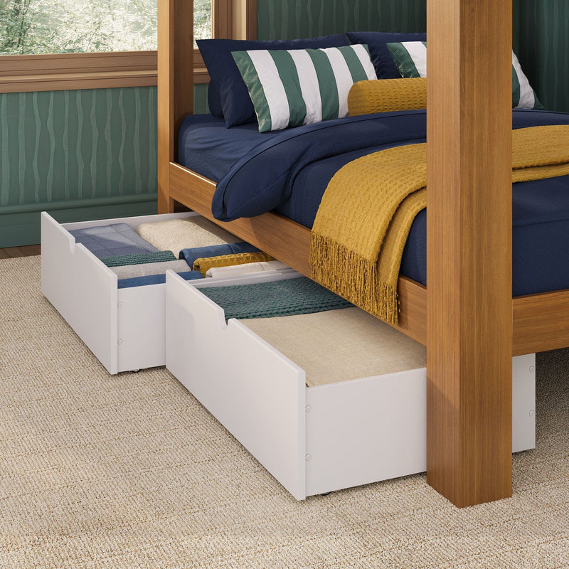 Solid wood canopy bed with navy bedding, green-striped pillows and mustard knit throw on carpet, showing white under-bed storage drawers