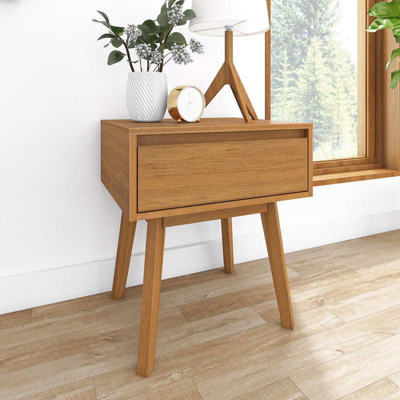 Mid-century modern wooden nightstand (bedside table) with single drawer and angled legs, styled with white ceramic vase, table lamp and gold alarm clock by window