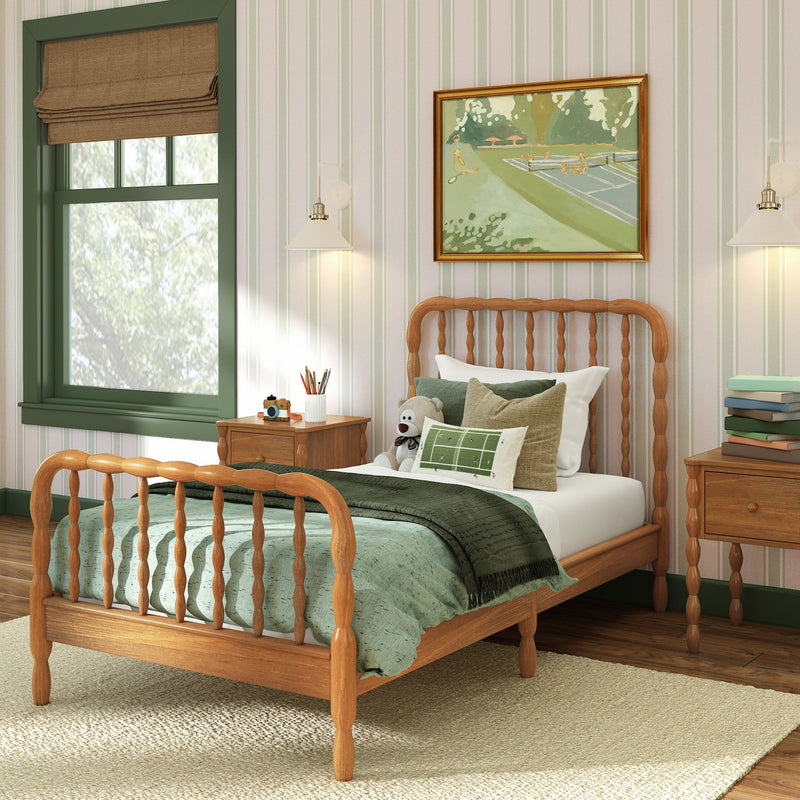 Cozy kids bedroom with wooden spindle twin bed, green bedding and pillows, striped wallpaper, green-trim window, bedside tables, lamp, teddy bear and framed artwork