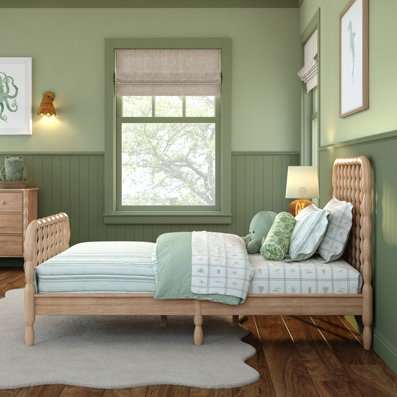 Cozy green children's bedroom with natural wood bed, mint bedding and pillows, plush frog toy, roman shade window, rattan lamp and sea-themed wall art