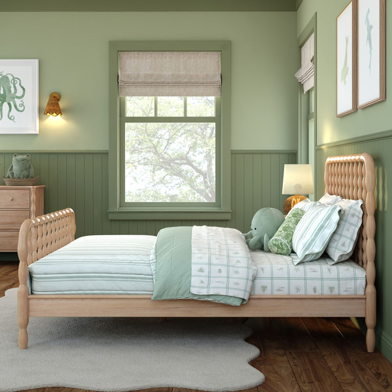 Coastal green children's bedroom with wooden spindle bed, mint striped bedding, plush octopus toy, rattan wall sconce, nautical wall art and a Roman shade window