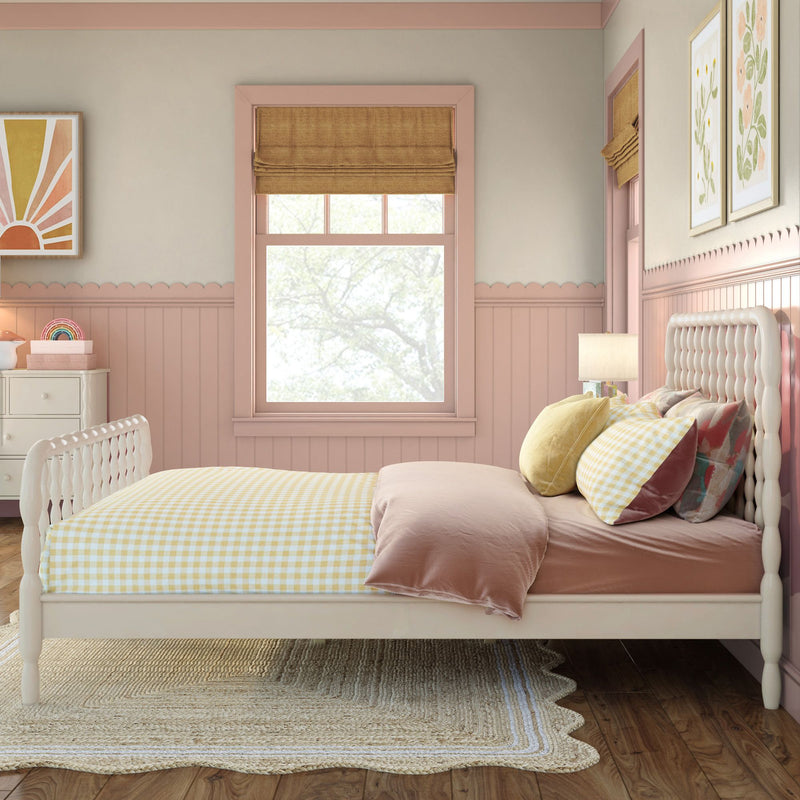 Pink girls' bedroom with tufted white headboard, yellow gingham bedding, scalloped pink wainscoting, roman shades and floral wall art