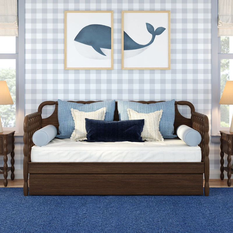 Coastal nursery bedroom with wooden daybed, blue and white pillows and navy whale framed prints on gray gingham wallpaper
