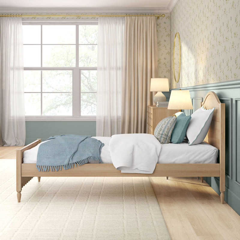 Bright coastal farmhouse bedroom with light wood bed, teal throw and pillows, floral wallpaper, bedside lamps and large window with sheer curtains