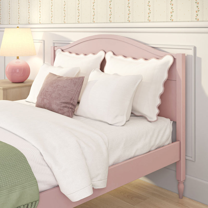 Cozy girl's bedroom with pink scalloped headboard, white bedding and pillows, pink table lamp and floral wallpaper