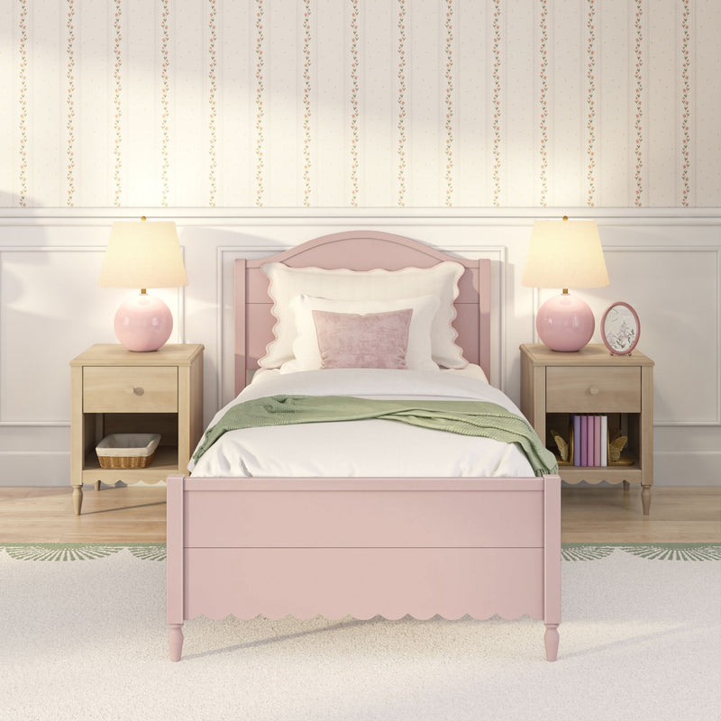 Pink scalloped twin bed with white bedding and green throw, matching nightstands and pink lamps in girls' bedroom with floral striped wallpaper