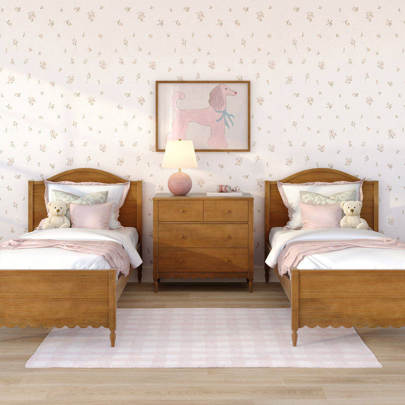 Pastel twin girls' bedroom with wooden twin beds, pink bedding and pillows, floral wallpaper, teddy bears, nightstand with lamp and framed pink poodle wall art