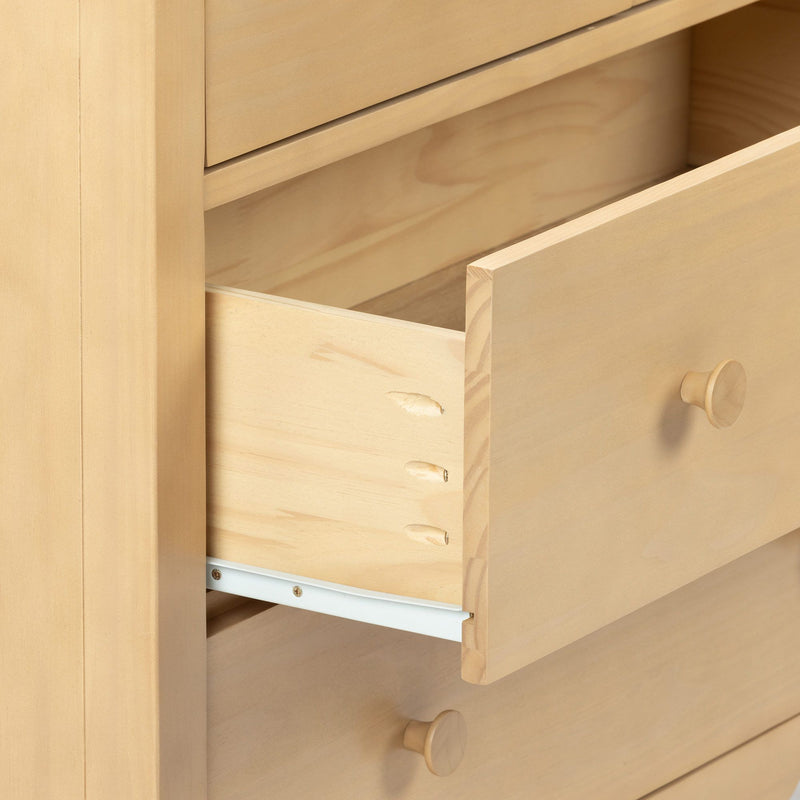Close-up of light wood dresser with open drawer, visible dovetail joints, wooden knob and metal drawer slide
