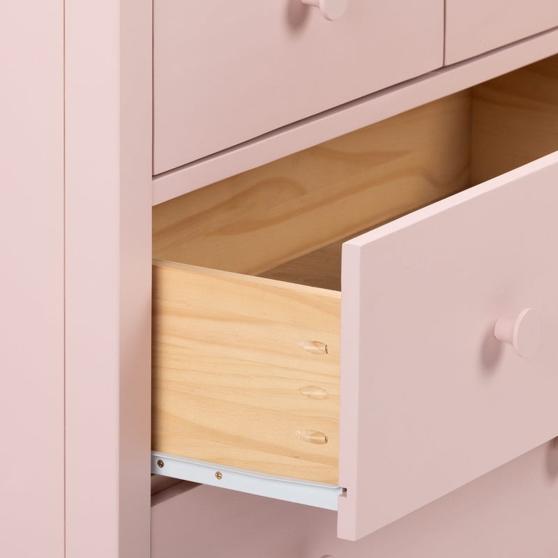 Pink nursery dresser with open drawer showing natural wood interior, round knob and smooth matte finish