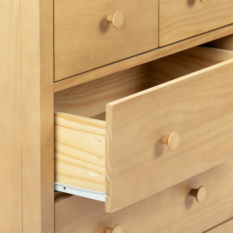 Close-up of solid pine chest of drawers with open drawers and round wooden knobs in a light natural finish