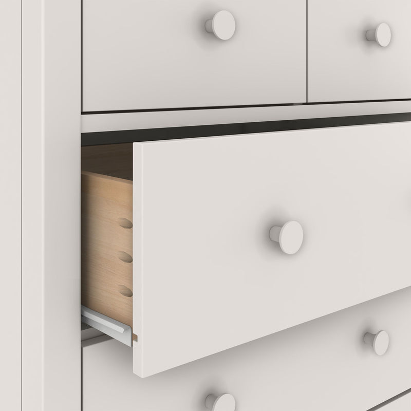 White painted bedroom dresser with partially open drawers revealing natural pine interiors and round white knobs