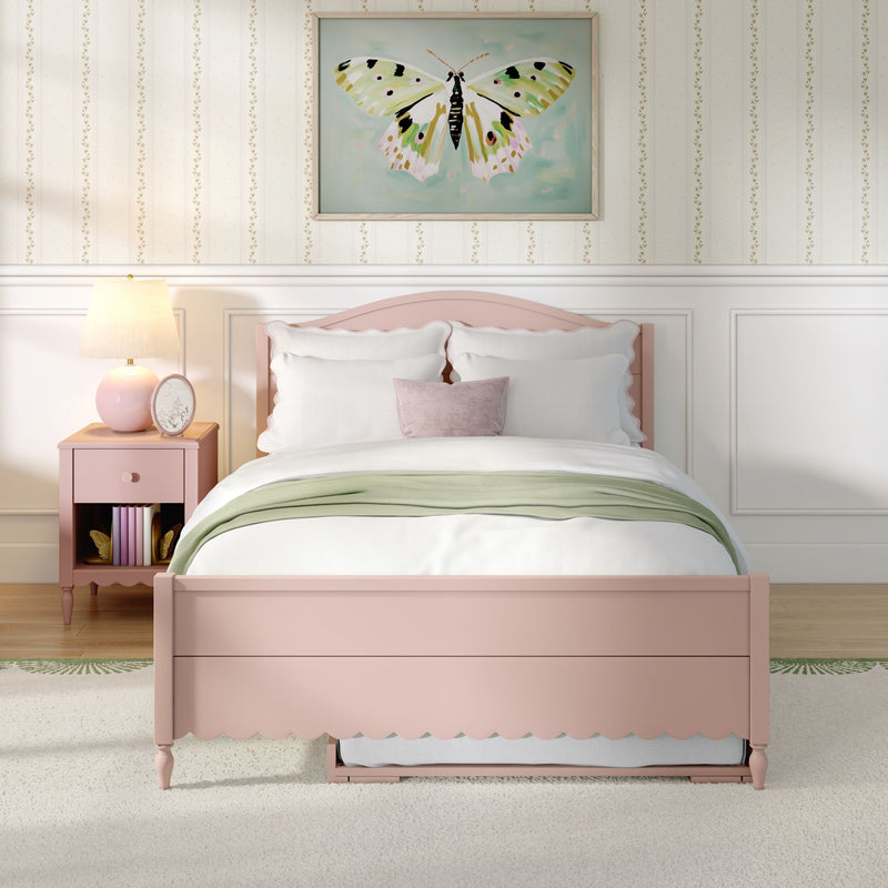 Pastel pink bedroom with scalloped twin bed, white bedding and green throw, framed butterfly wall art, pink nightstand and lamp