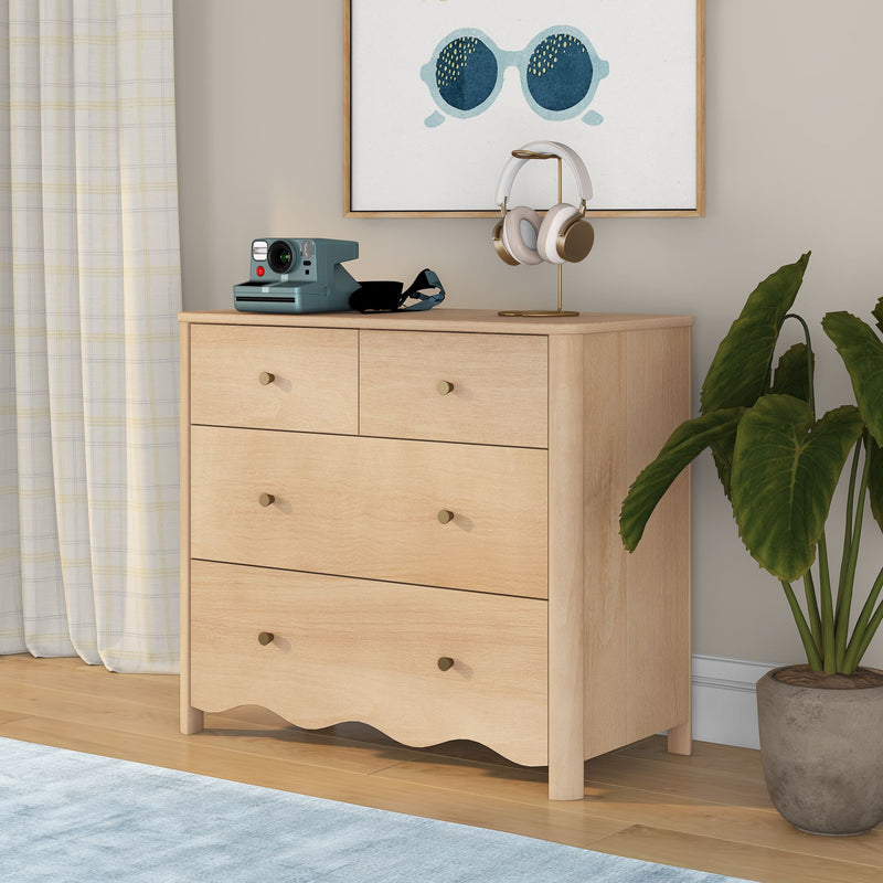 Light wood dresser topped with white-and-gold over-ear headphones on a stand and a retro teal instant camera, framed sunglasses print, potted green plant and plaid curtains in a neutral modern bedroom.