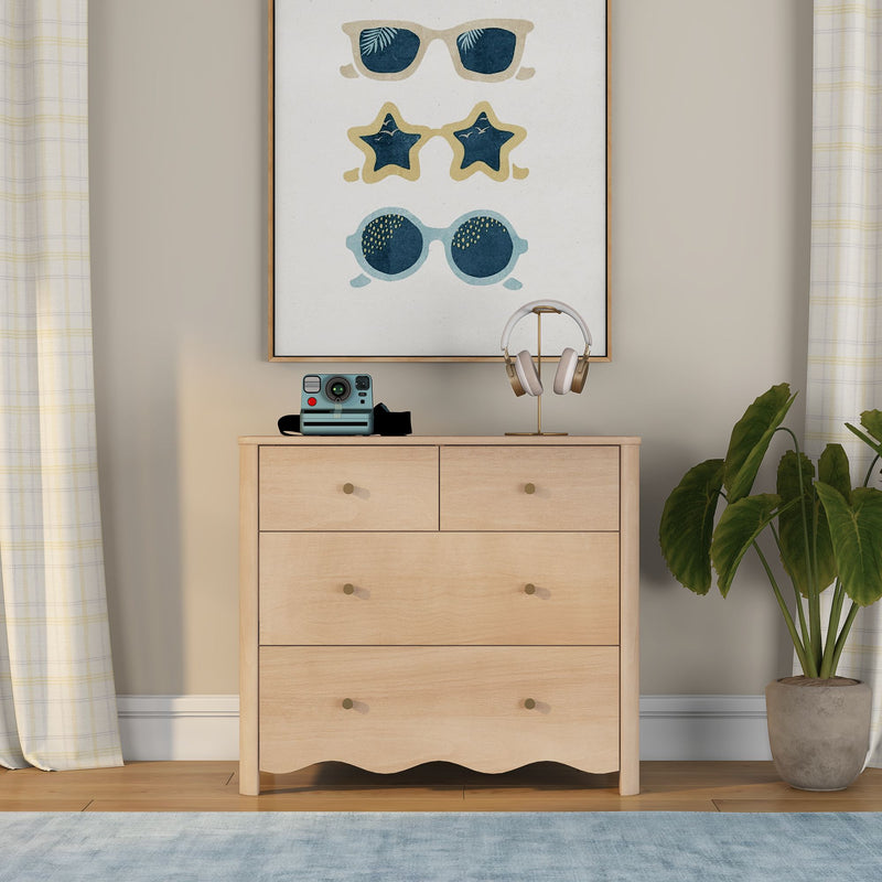 Light wood dresser with framed sunglasses wall art, gold headphone stand, vintage instant camera and potted plant in neutral bedroom decor
